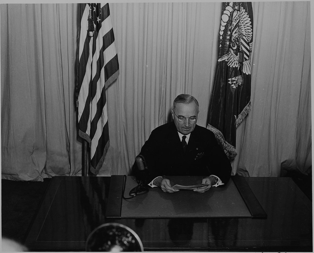 1273px-President_Harry_S._Truman_seated_at_a_desk,_before_a_microphone,_announcing_the_end_of_World_War_II_in_Europe._-_NARA_-_199078