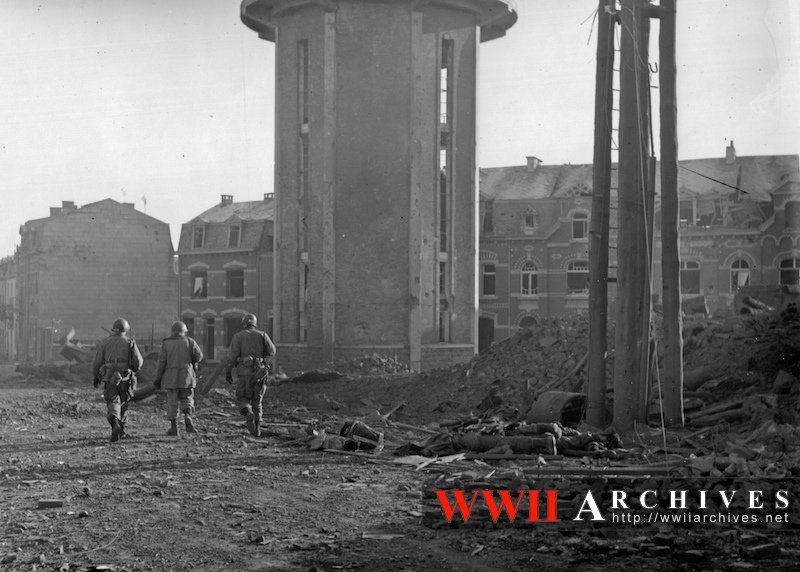 Members of 101st Airborne Division walk past comrades killed during the Christmas Eve bombing of Bastogne, Belgium, 12/23/1944