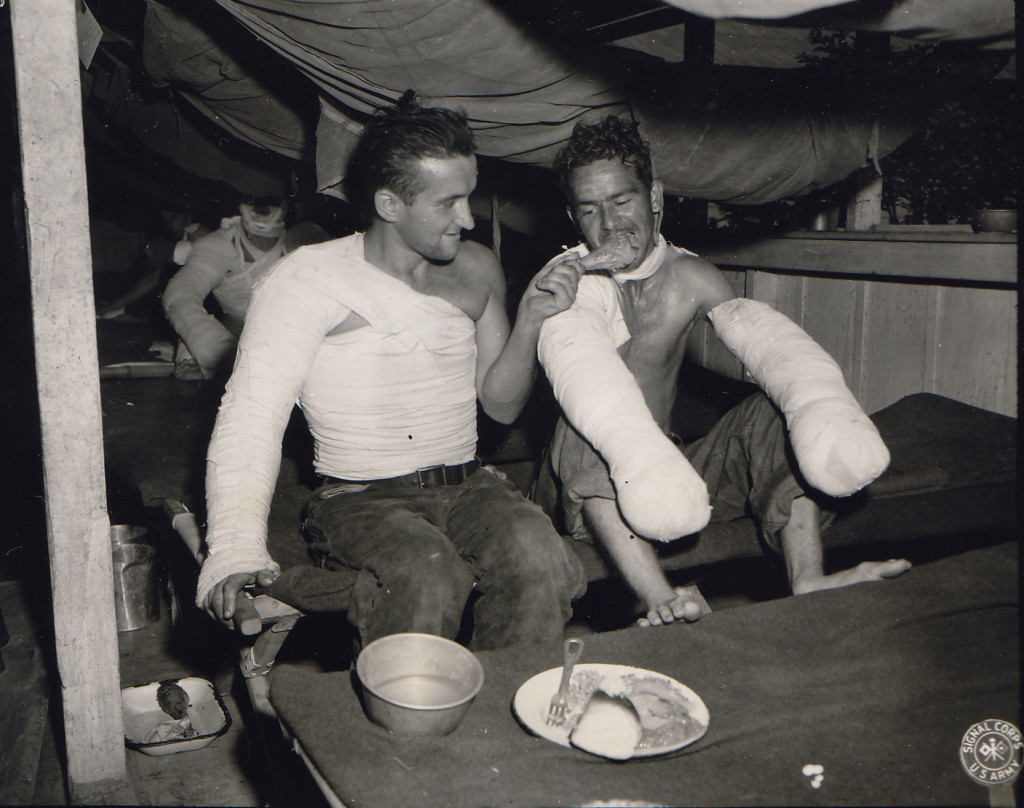 US Army Sgt. Edward F. Good feeding Pfc. Lloyd Demin during the Christmas dinner at a field hospital in the Philippine Islands, 25 Dec 1944