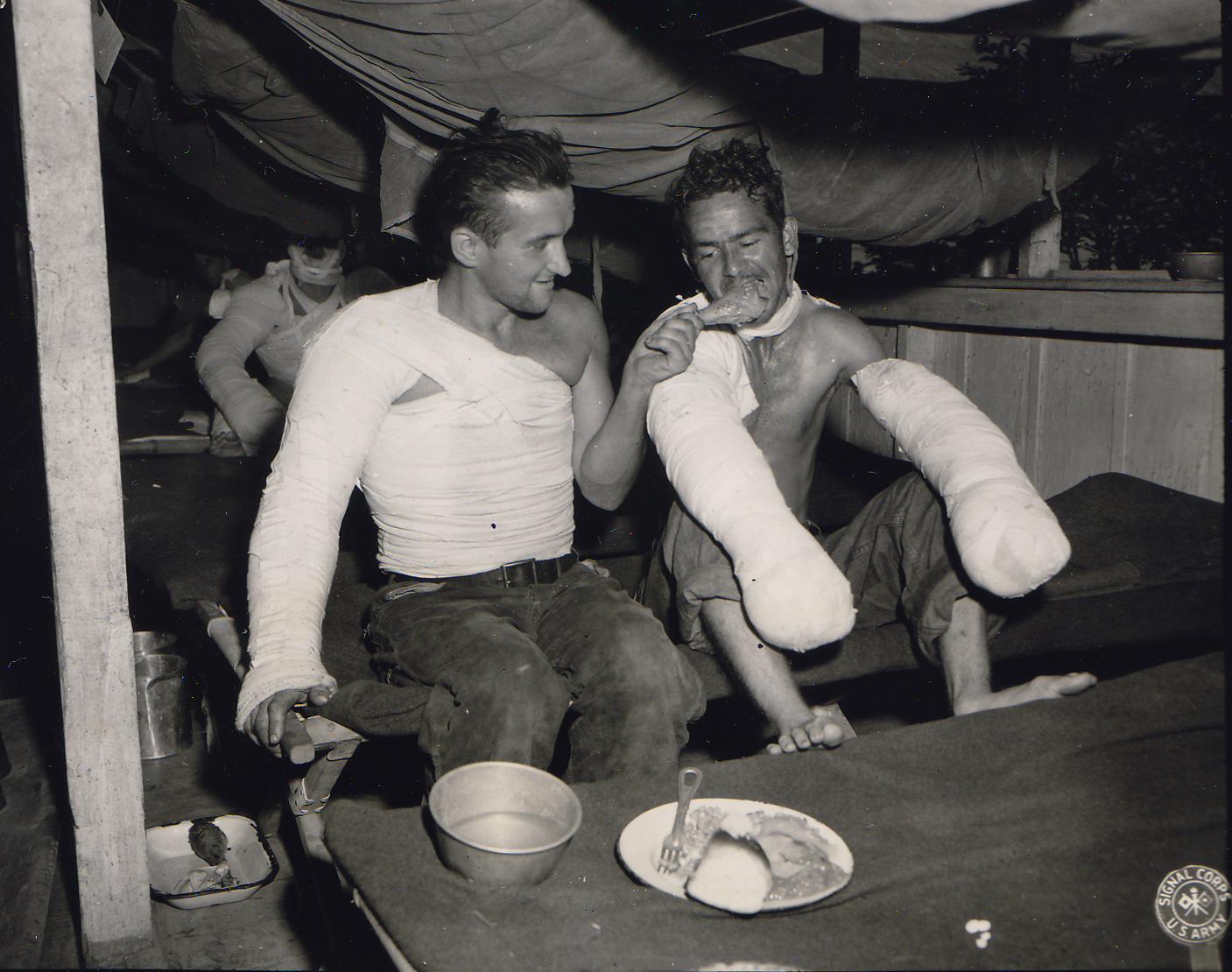 US Army Sgt. Edward F. Good feeding Pfc. Lloyd Demin during the Christmas dinner at a field hospital in the Philippine Islands, 12/25/1944