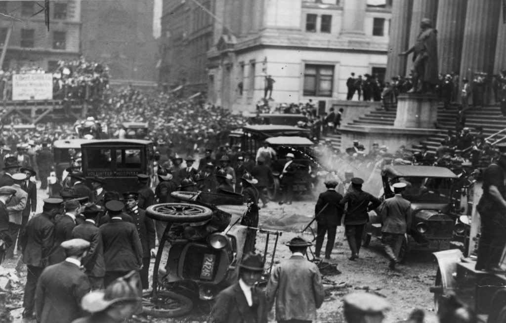 Crowd_gathered_following_the_explosion_on_Wall_St._car_overturned_in_foreground_ambulance_behind_it_LCCN2003663321 (1)