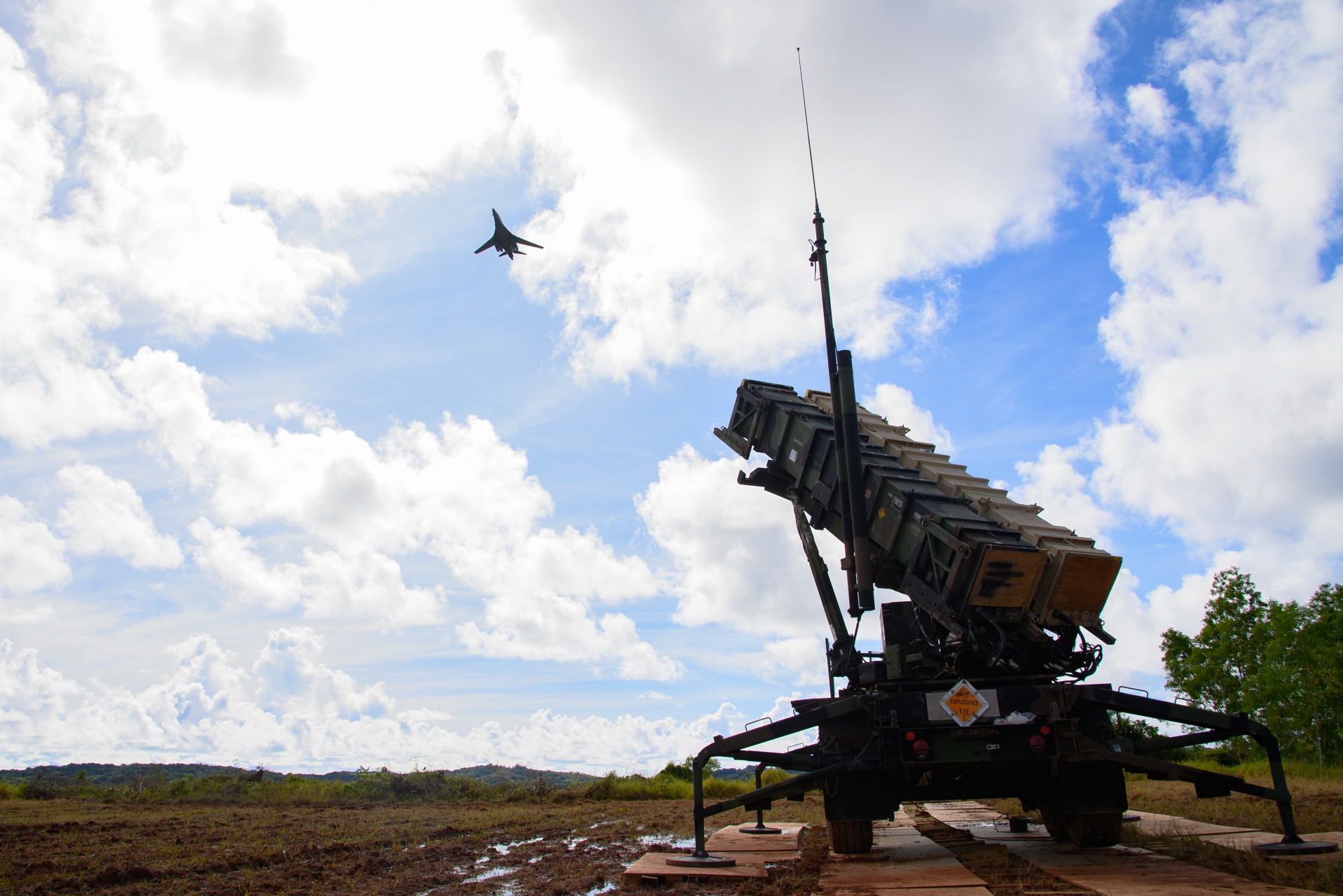 A U.S. Air Force B-1B Lancer assigned to the 34th Expeditionary Bomb Squadron flies over a MIM-104 Patriot missile launcher assigned to the Charlie Battery, 1-1 Air Defense Artillery Battalion at Palau International Airport in support of Valiant Shield 22