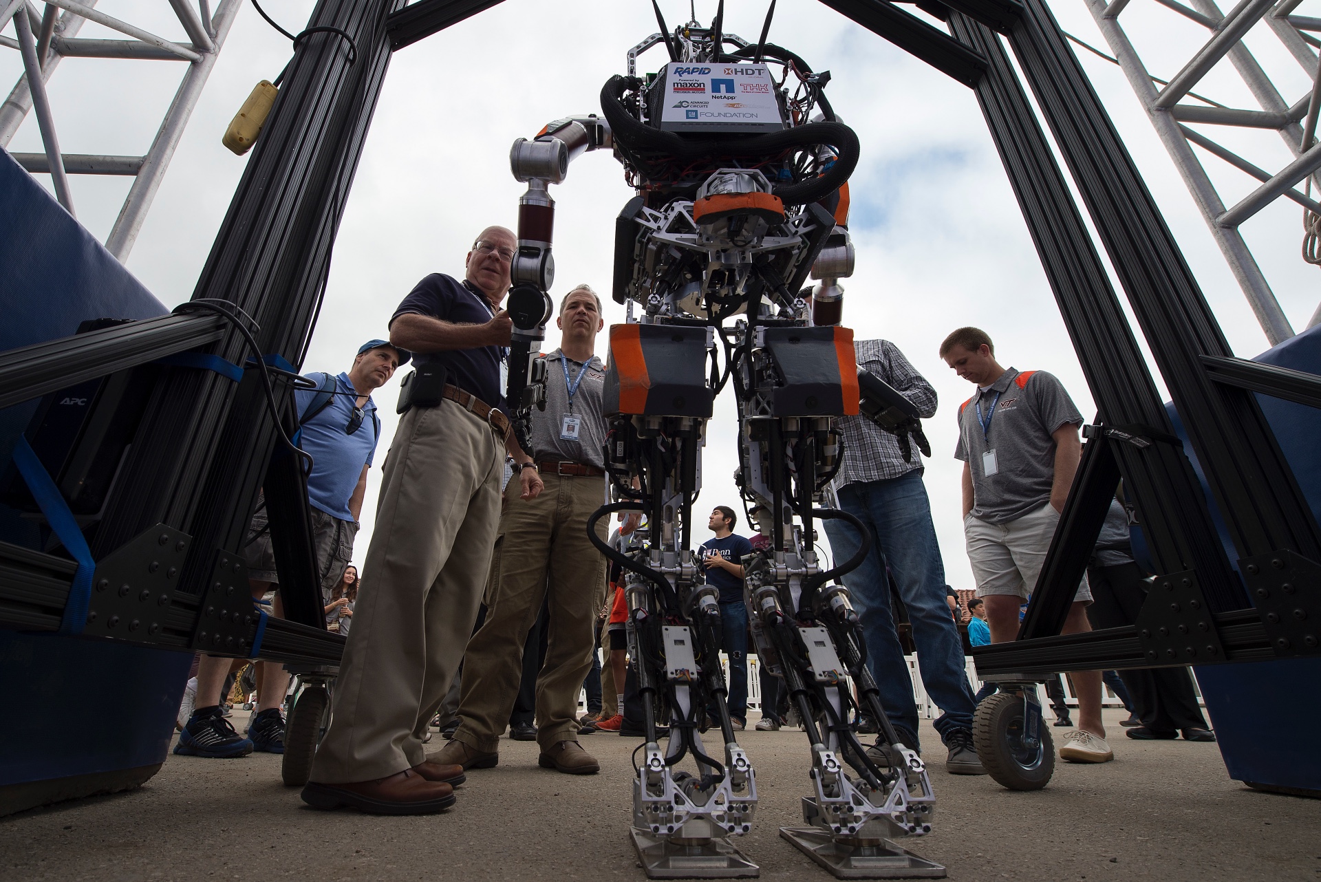 DARPA officials stand next to a robot during a competition