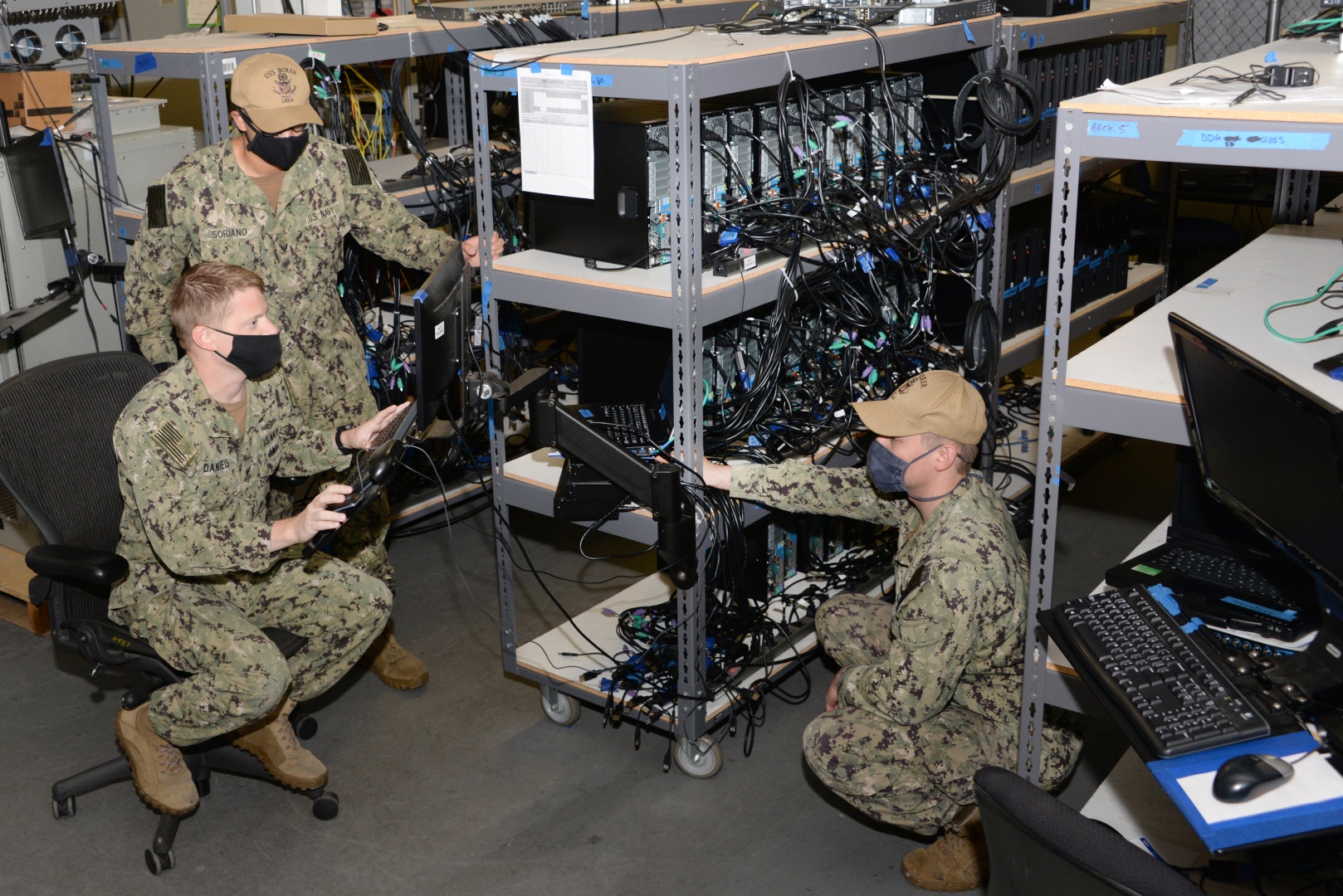 A Navy sailor explains software loading procedures to visiting Information Systems Technicians from USS Boxer