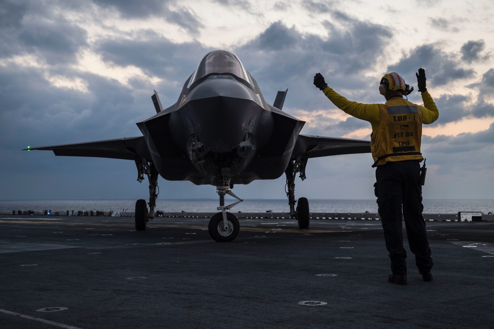 Aviation Boatswain's Mate (Handling) 1st Class James Spencer directs an F-35B Lightning II aircraft belonging to Marine Fighter Attack Squadron 121, the fixed wing component of 31st Marine Expeditionary Unit's (MEU) Aviation Combat Element, on the flight deck of the amphibious assault ship USS Wasp