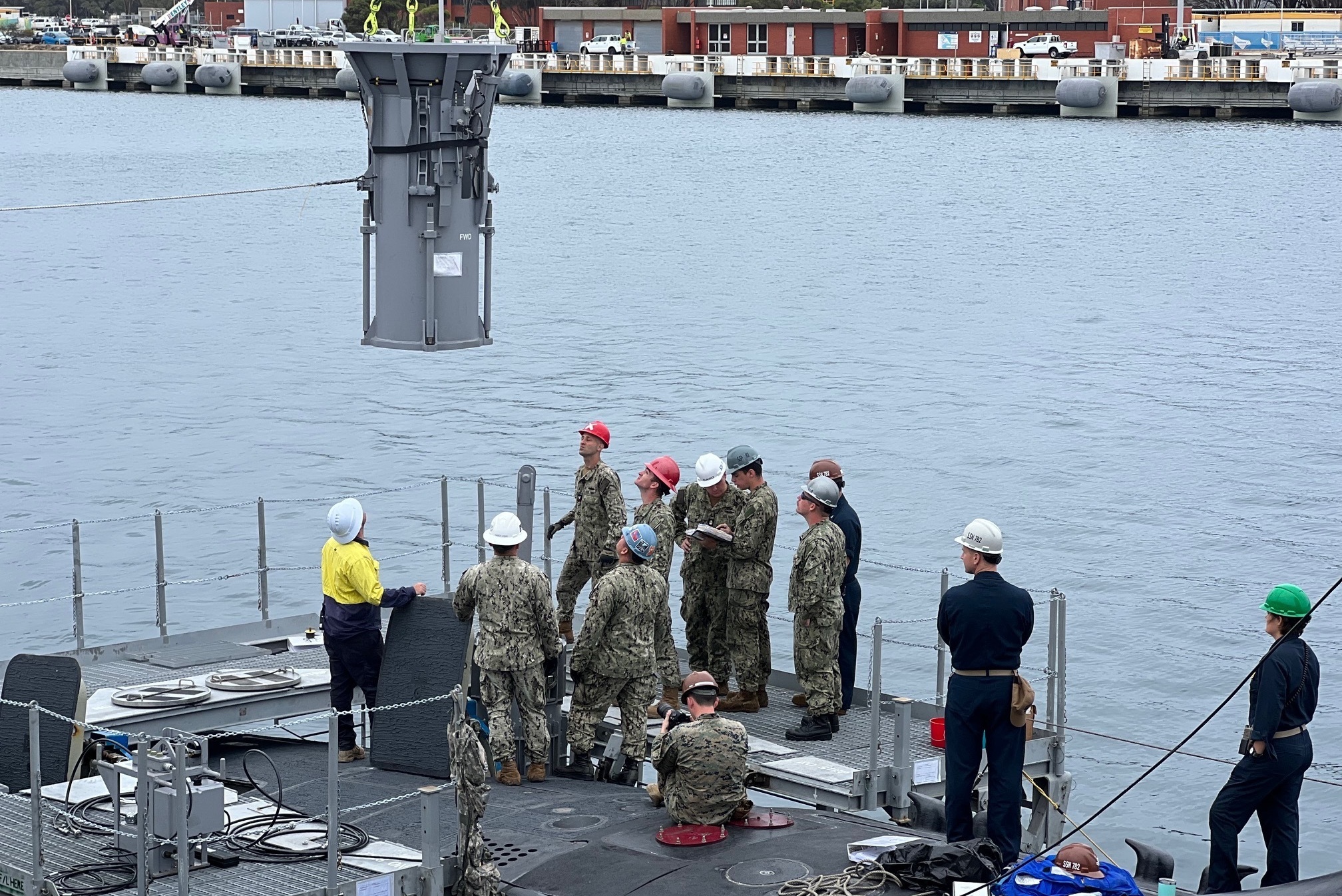 U.S. Navy Sailors assigned to the Virginia-class fast-attack submarine USS Mississippi (SSN 782), Sailors assigned to Navy Munitions Command East Asia Division Unit Guam, and explosive ordnance support personnel from Thales Australia participate in a weapons-handling training exercise with a Tomahawk Land Attack Missile training shape aboard the submarine while moored at HMAS Stirling Navy Base on Garden Island, Dec. 1